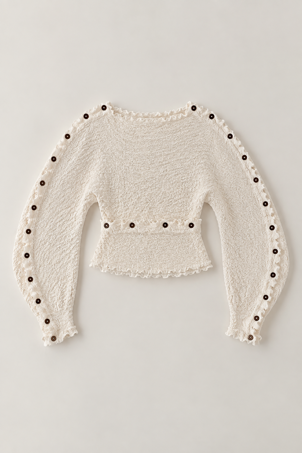 An off-white textured knit long-sleeve crop top with dark brown decorative buttons along the sleeve edges and waist, displayed flat against a light gray background.