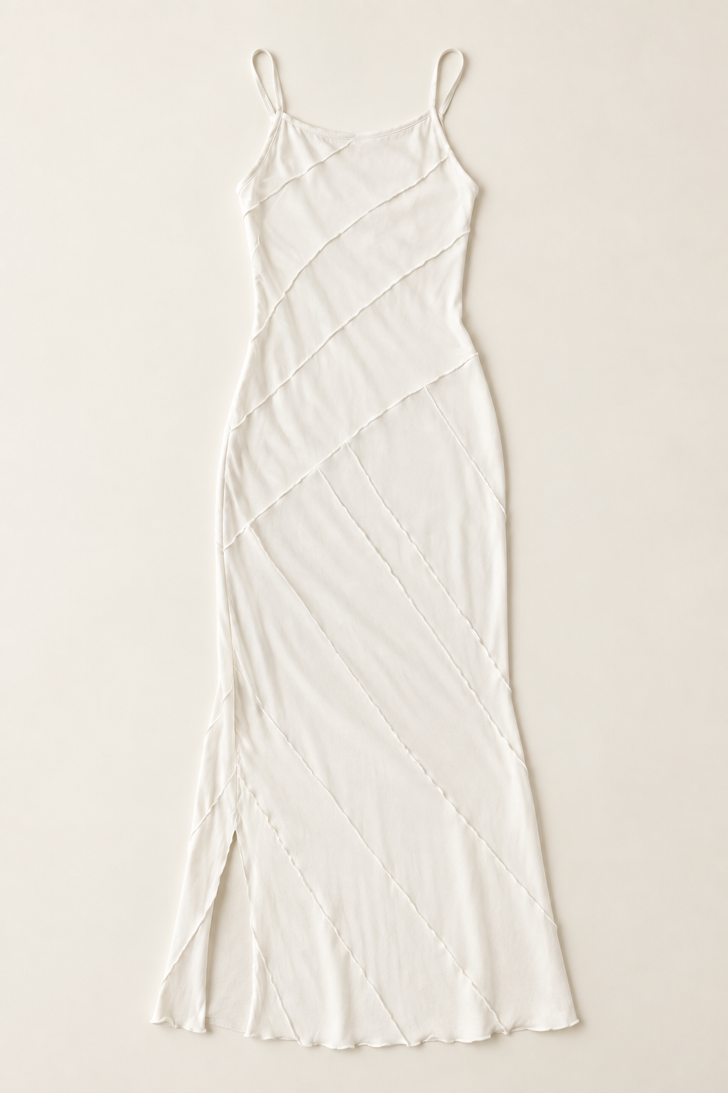 An off-white spaghetti-strap midi dress with diagonal textured stitching, laid flat against a solid beige background.