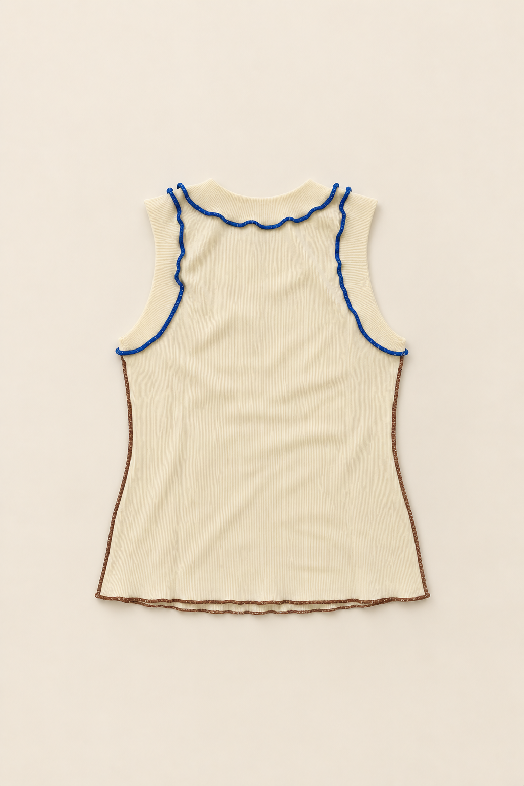 An off-white sleeveless knit top with blue scalloped trim at the neckline and brown scalloped trim along the armholes and hem, laid flat on a light beige background.